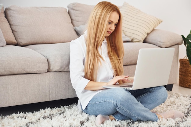 Jeune femme en chemise blanche et jeans à l'intérieur