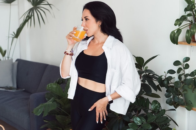 Jeune femme en chemise blanche avec verre de jus d'orange