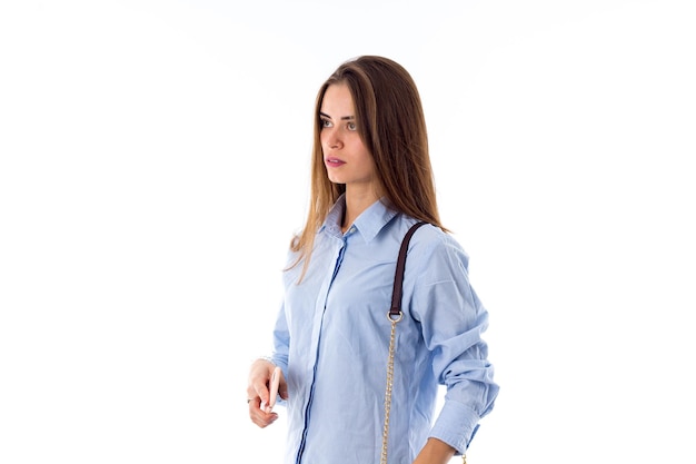 Jeune femme en chemise bleue et jeans avec petit sac à l'aide de son téléphone portable rose