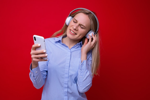 Une jeune femme en chemise écoute de la musique depuis son téléphone