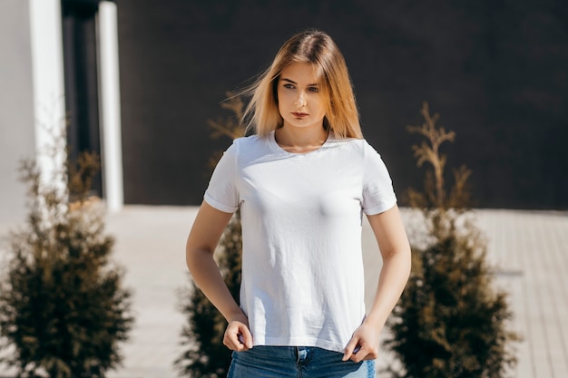 Jeune femme en chemise et jeans posant à l'extérieur