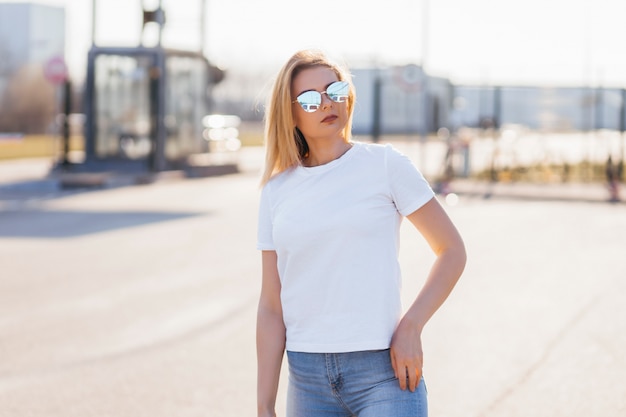 Jeune femme en chemise et jeans posant à l'extérieur