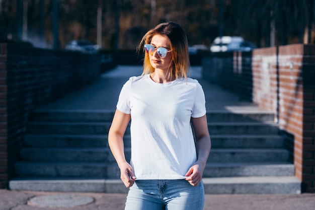 Jeune femme en chemise et jeans posant à l'extérieur