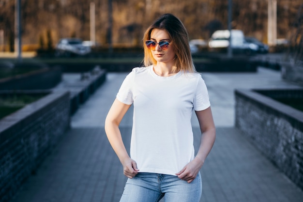 Jeune femme en chemise et jeans posant à l'extérieur