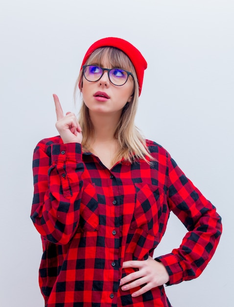 Jeune femme en chemise rouge et bonnet avec des lunettes