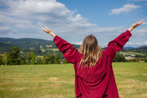 Jeune femme en chemise rouge s'amuser dans les montagnes