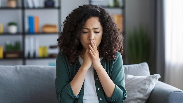 Une jeune femme en chemise verte souffre de toux et a l'air malade.