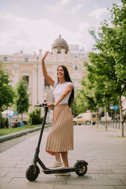 Jeune femme chevauchant un scooter électrique dans une rue