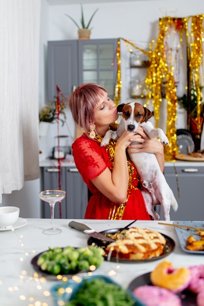 Jeune femme avec un chien assis dans une cuisine après la fête