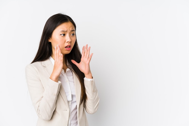 Jeune femme chinoise d'affaires isolée crie fort, garde les yeux ouverts et les mains tendues.