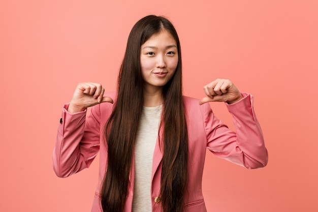 Jeune femme chinoise d'affaires portant un costume rose se sent fière et sûre d'elle, exemple à suivre.