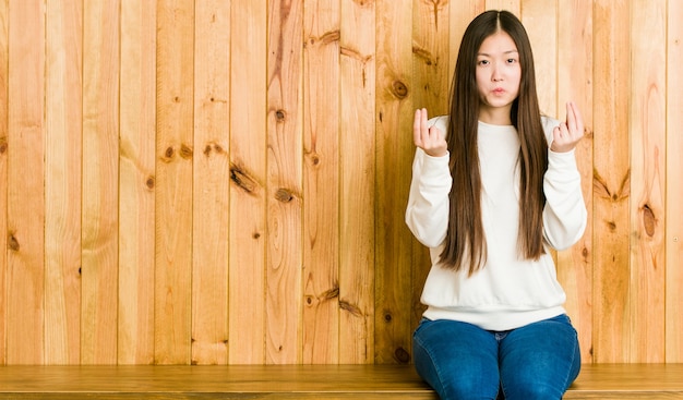 Jeune femme chinoise assise sur une place en bois montrant qu'elle n'a pas d'argent.