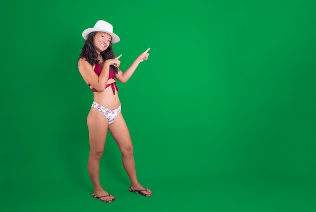 Jeune femme chinoise en bikini pointant vers quelque chose à côté d'elle souriant en incrustation chroma