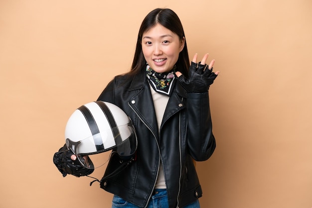 Jeune femme chinoise avec un casque de moto isolé sur fond beige comptant cinq avec les doigts