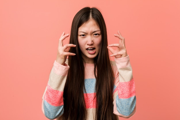 Jeune femme chinoise cool bouleversée crier avec les mains tendues.