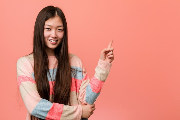 Jeune femme chinoise cool souriant joyeusement pointant avec l'index loin.