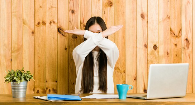 Photo jeune femme chinoise étudie sur son bureau en gardant deux bras croisés, concept de déni.