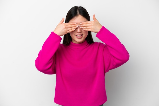 Jeune femme chinoise isolée sur fond blanc couvrant les yeux par les mains et souriant