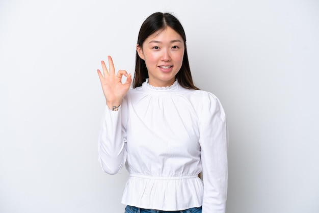 Jeune femme chinoise isolée sur fond blanc montrant signe ok avec les doigts