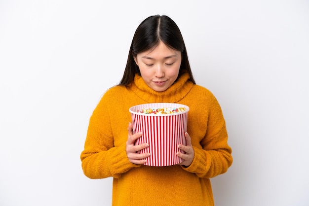 Jeune femme chinoise isolée sur fond blanc tenant un grand seau de pop-corn