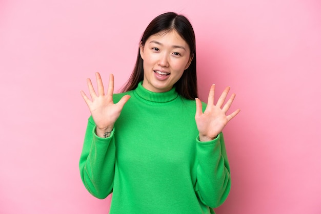 Jeune femme chinoise isolée sur fond rose comptant dix avec les doigts