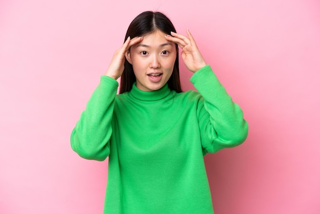 Jeune femme chinoise isolée sur fond rose avec une expression surprise