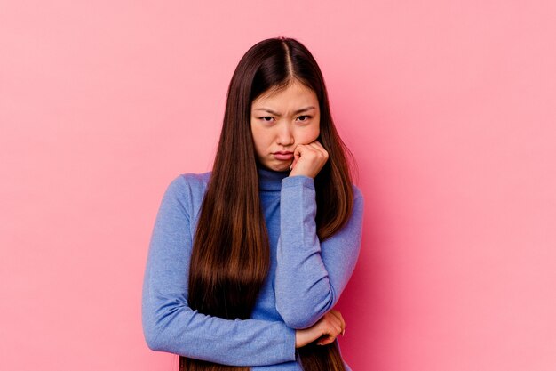 Jeune femme chinoise isolée sur fond rose fatiguée d'une tâche répétitive.