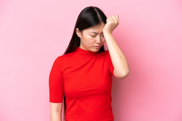 Jeune femme chinoise isolée sur fond rose avec maux de tête