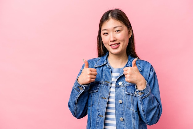 Jeune femme chinoise isolée sur fond rose souriant et levant le pouce vers le haut