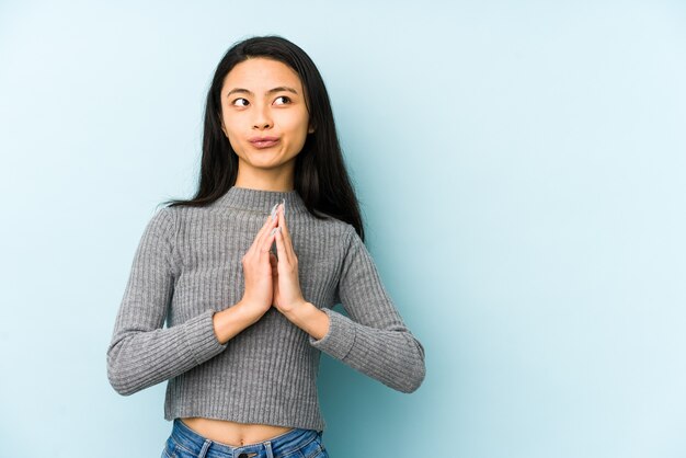 Jeune femme chinoise isolée sur un mur bleu faisant plan à l'esprit, mettant en place une idée.