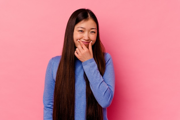 Jeune femme chinoise isolée sur un mur rose doutant entre deux options.