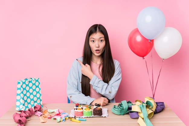 Jeune femme chinoise organisant un anniversaire isolé pointant vers le côté