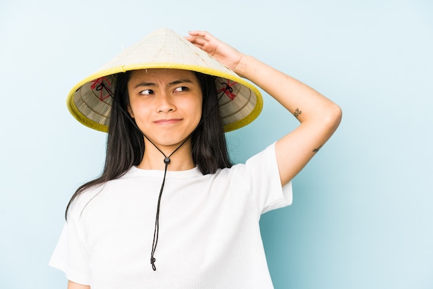 Jeune femme chinoise portant un foin vietnamien isolé essayant d'écouter un potin.
