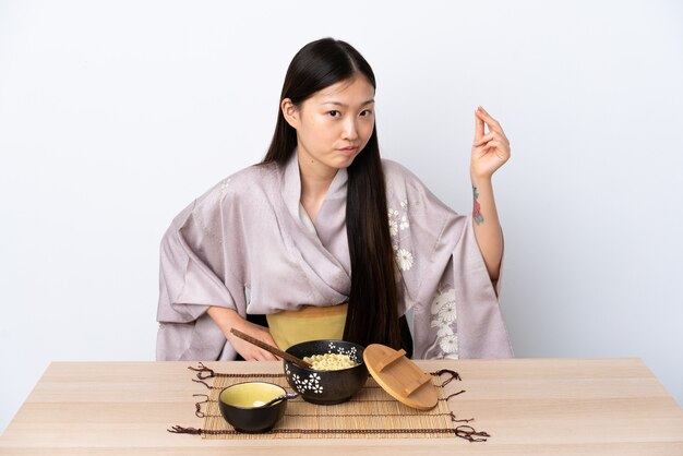 Jeune femme chinoise portant un kimono et manger des nouilles faisant geste italien