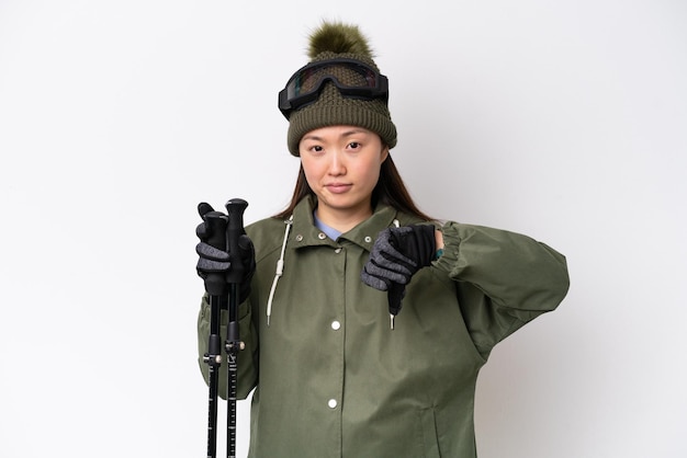 Jeune femme chinoise portant une veste d'hiver isolée sur fond blanc montrant le pouce vers le bas avec une expression négative