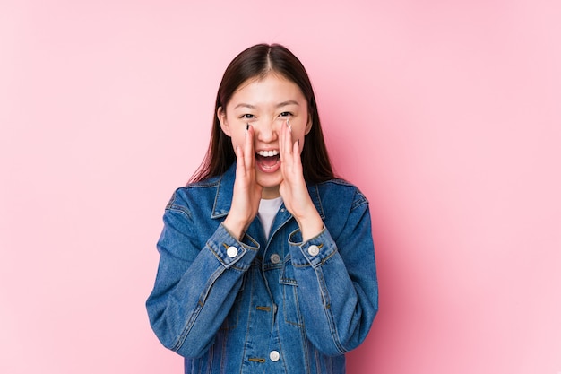 Jeune femme chinoise posant sur des cris isolés roses excités à l'avant.