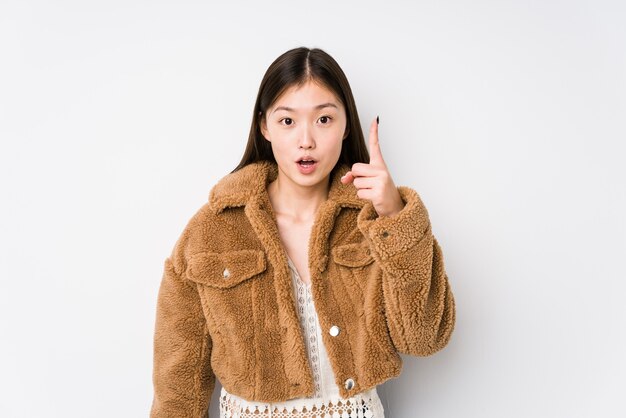 Jeune femme chinoise posant dans un mur blanc isolé ayant une idée, un concept d'inspiration.