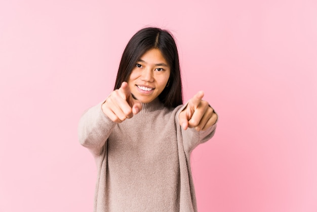 Jeune femme chinoise posant des sourires joyeux isolés pointant vers l'avant.