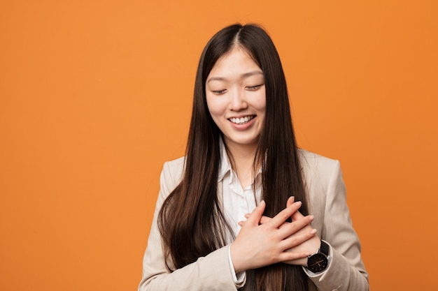 Jeune femme chinoise en riant en gardant les mains sur le cœur, le concept du bonheur.