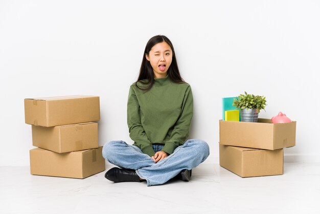 Jeune femme chinoise se déplaçant vers une nouvelle maison drôle et sympathique qui sort la langue.