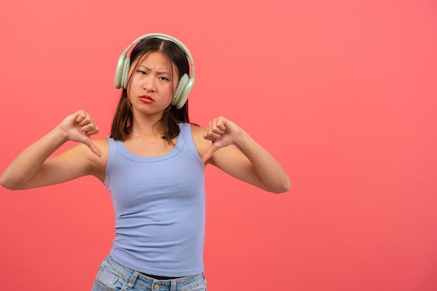 jeune femme chinoise sérieuse pointant des doigts vers le bas sur un fond rose