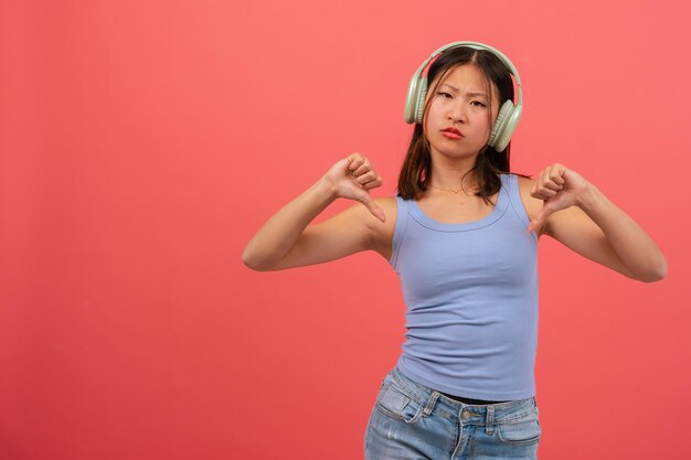 jeune femme chinoise sérieuse pointant des doigts vers le bas sur un fond rose