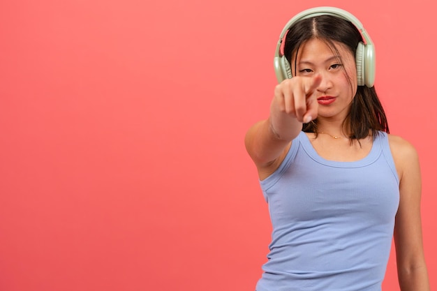 une jeune femme chinoise sérieuse pointant du doigt sur un fond rose