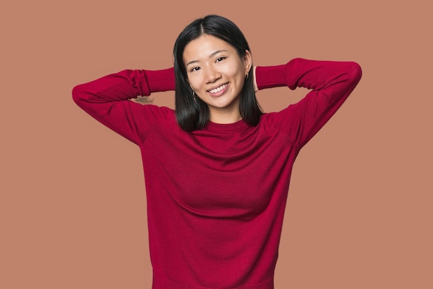 Jeune femme chinoise en studio tendant les bras en position détendue
