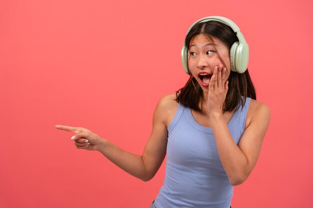 jeune femme chinoise surprise pointant du doigt sur un fond rose