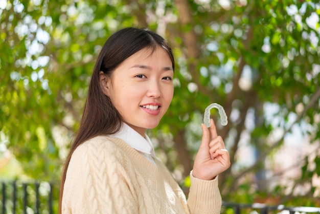 Jeune femme chinoise tenant des accolades invisibles à l'extérieur souriant beaucoup