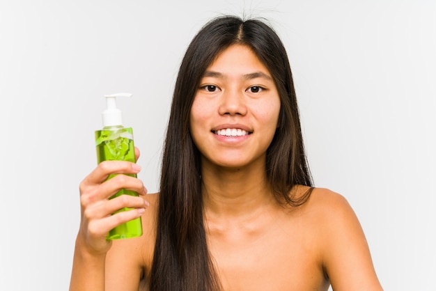 Jeune femme chinoise tenant une crème hydratante à l'aloe vera isolé heureux, souriant et gai.