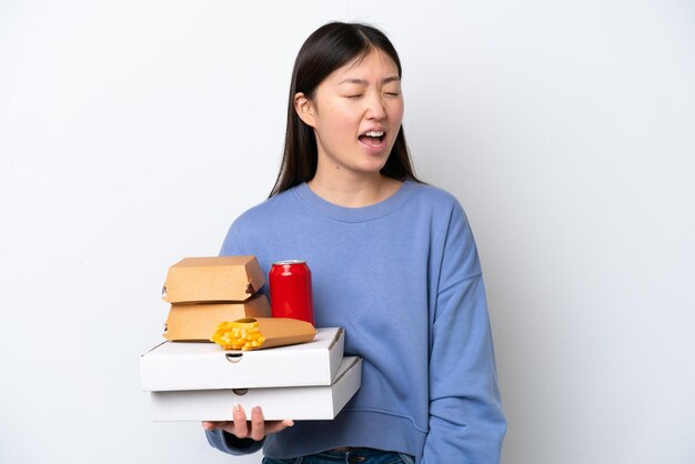 Jeune femme chinoise tenant une restauration rapide isolée sur fond blanc en riant en position latérale