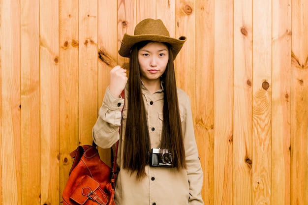 Jeune femme chinoise voyageant montrant le poing avec une expression faciale agressive.