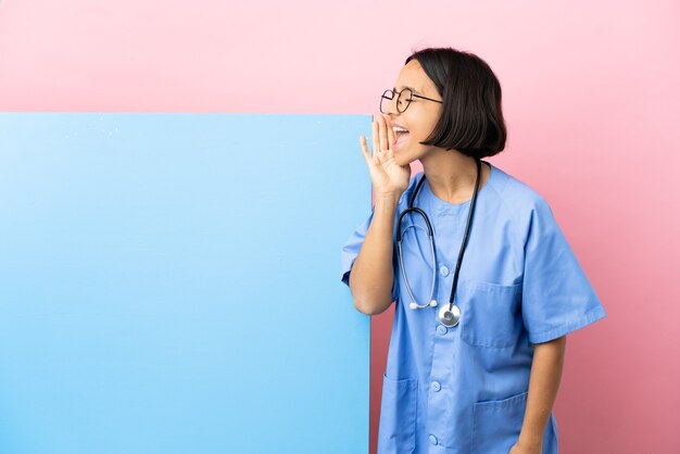 Jeune femme chirurgien métisse avec une grande bannière sur fond isolé criant avec la bouche grande ouverte sur le côté